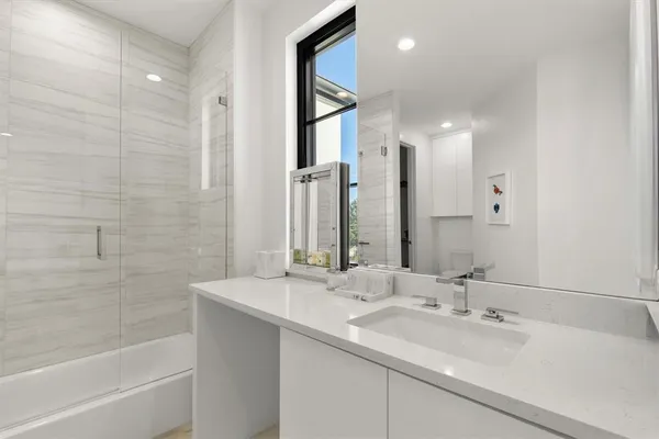 a bathroom with a double vanity sink mirror and a bathtub