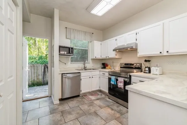 a kitchen with a sink a stove top oven and cabinets