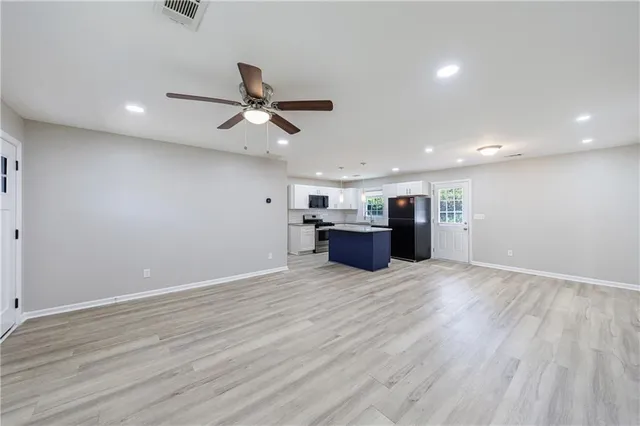 an empty room with wooden floor ceiling fan and windows