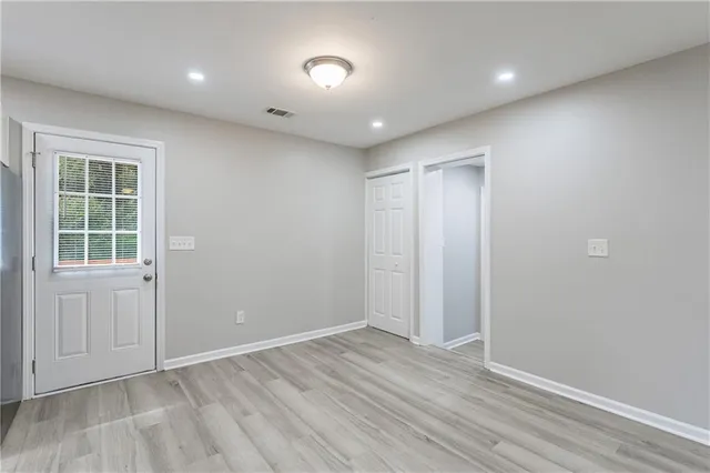 an empty room with wooden floor and kitchen view