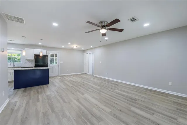 a view of kitchen and empty room with wooden floor
