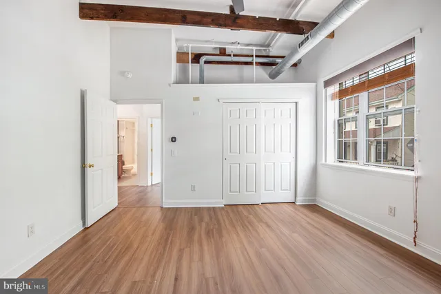 an empty room with wooden floor and windows
