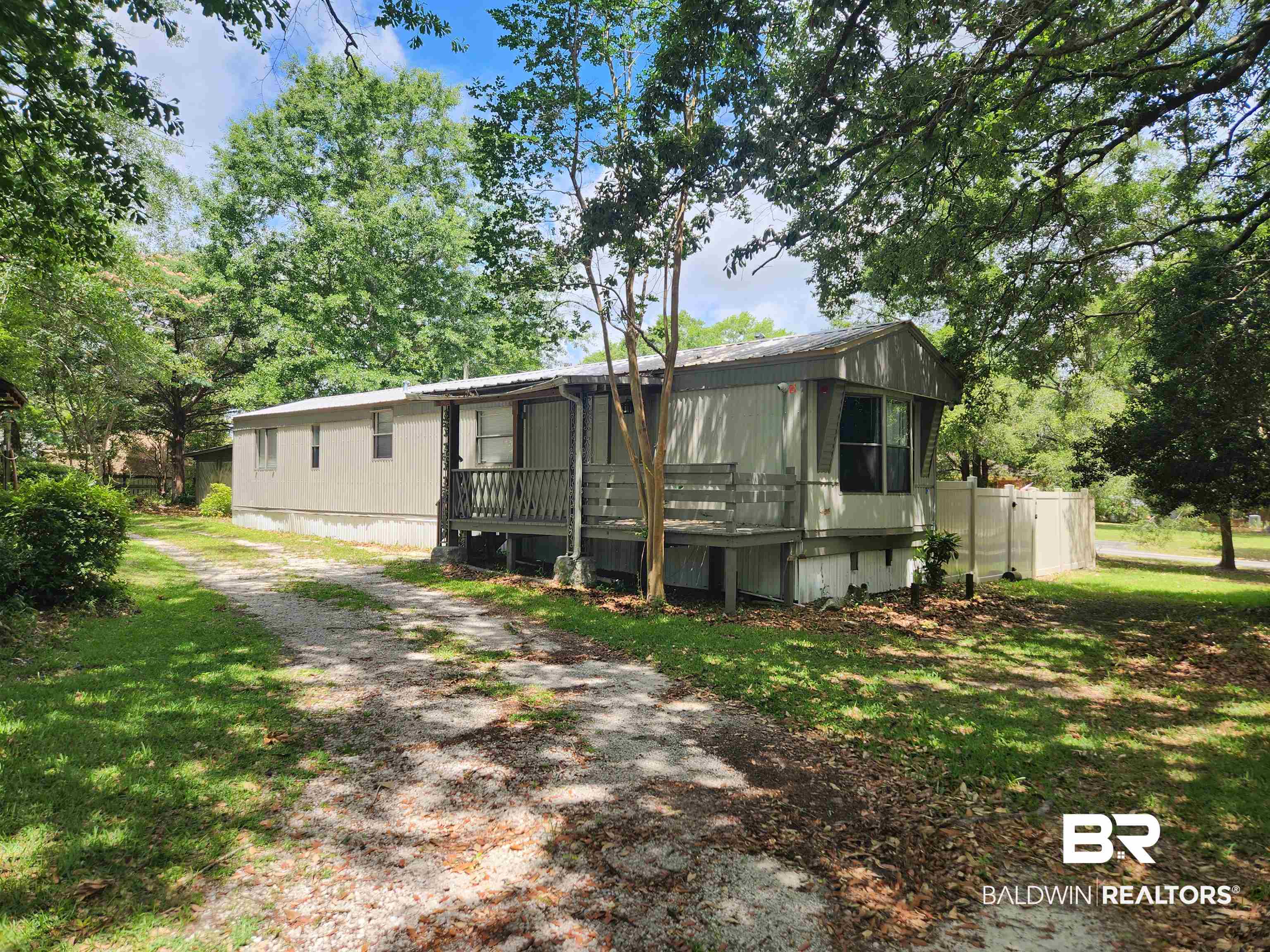 23051 Fritz Lane Foley, AL 36535 - Photo 1 of 26 Single-story residence featuring a covered front porch with railings, a gravel driveway, and a partially fenced yard