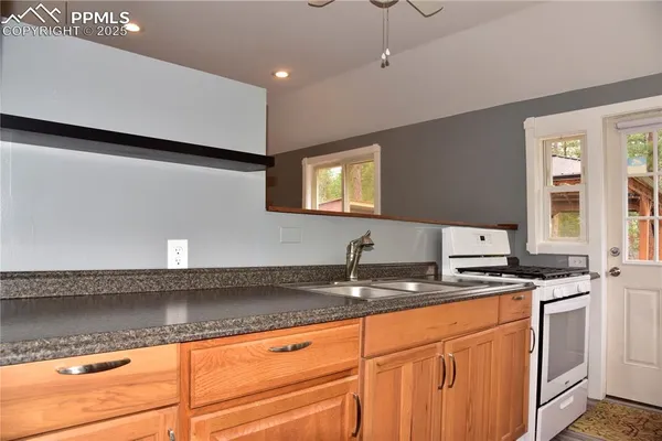 a kitchen with granite countertop a sink a stove and cabinets