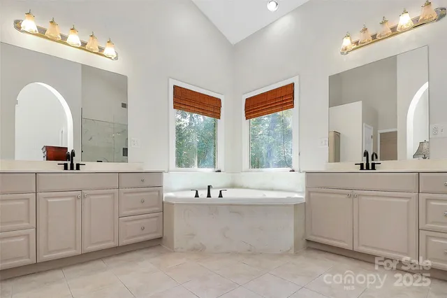 a spacious bathroom with a double vanity sink mirror and bathtub