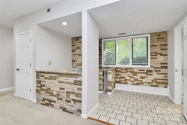 a view of an empty room with window and a kitchen