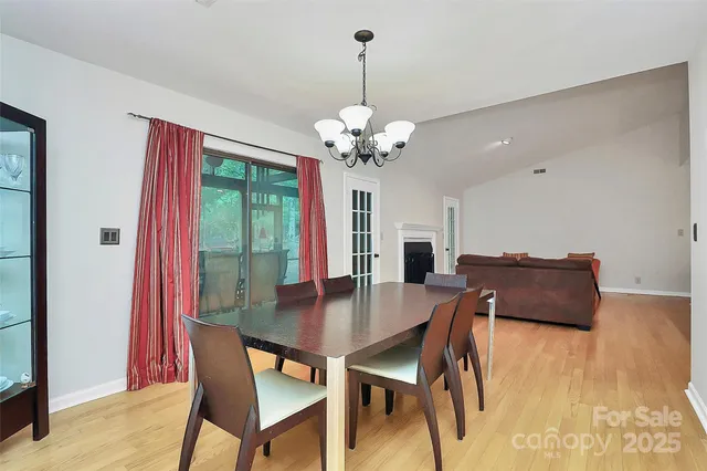 a dining room with wooden floor a chandelier a wooden table and chairs