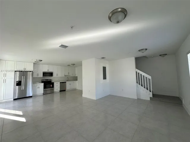 a view of a livingroom with kitchen and staircase