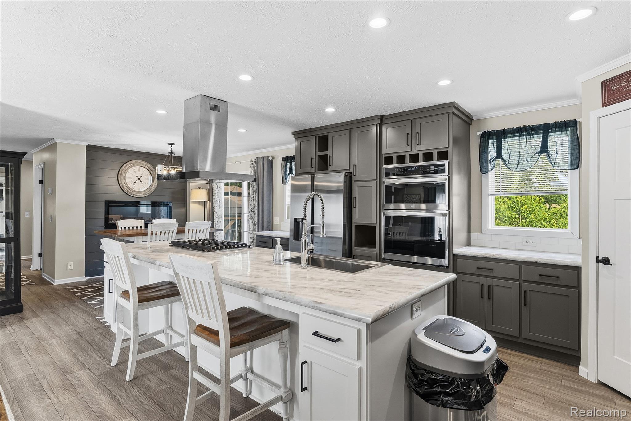 6450 Prince Boulevard Fenton, MI 48430 - Photo 14 of 31 Spacious kitchen featuring a large island with sink, stainless steel appliances, grey cabinetry, double wall ovens, and wood-finish flooring