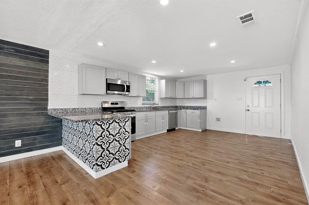 2519 Maverick Avenue Dallas, TX 75228 - Photo 7 of 31 a kitchen with stainless steel appliances granite countertop a stove a sink dishwasher a refrigerator and white cabinets with wooden floor