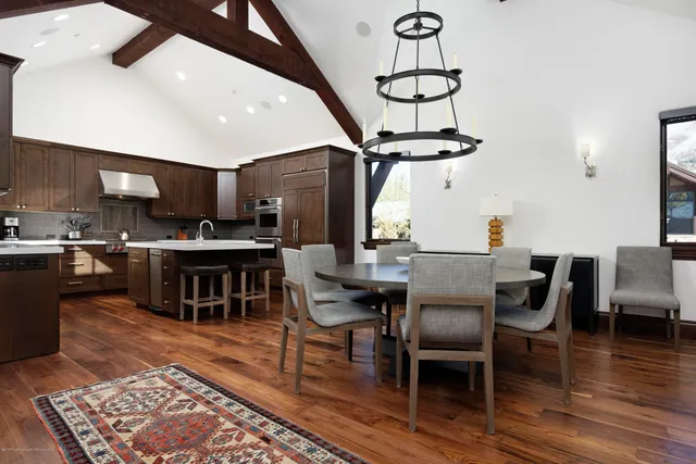 a kitchen with stainless steel appliances granite countertop a table chairs and a wooden floor