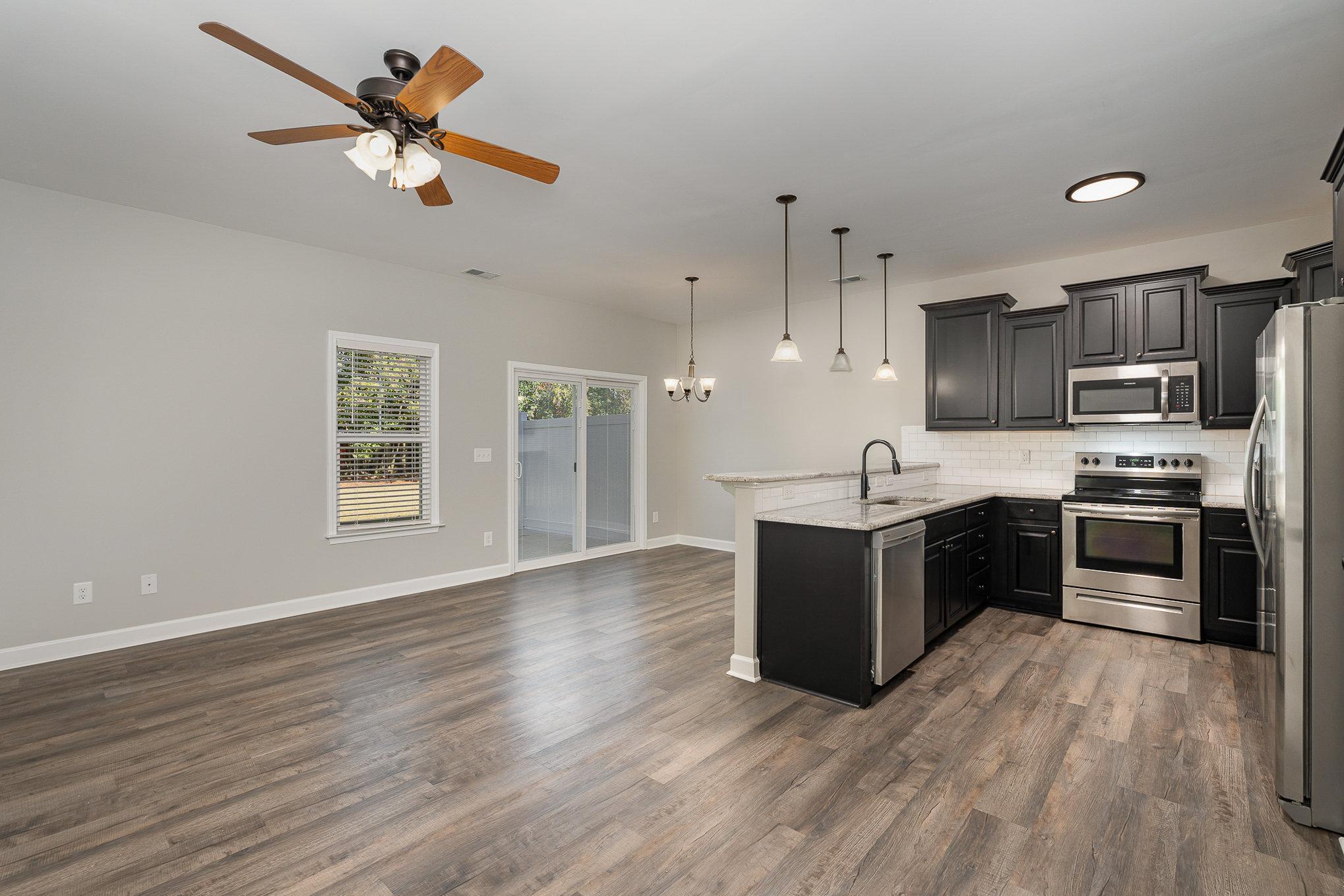 407 East 3rd Street Princeton, NC 27569 - Photo 3 of 18 a kitchen with stainless steel appliances kitchen island granite countertop a stove a refrigerator a sink a microwave oven with wooden floor and cabinets