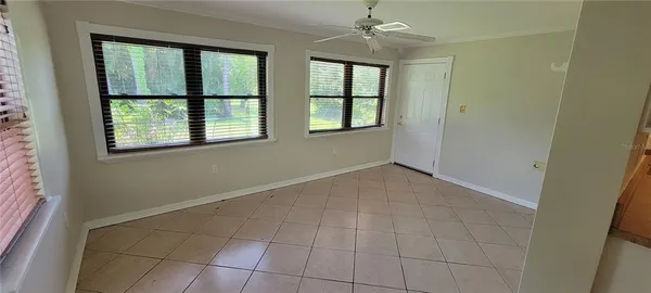 an empty room with windows and chandelier fan