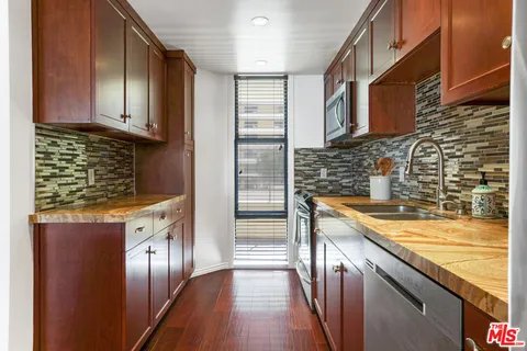 a kitchen with stainless steel appliances granite countertop a refrigerator a sink and wooden cabinets