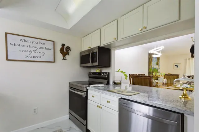 a kitchen with stainless steel appliances granite countertop a sink a stove a microwave and wooden cabinets