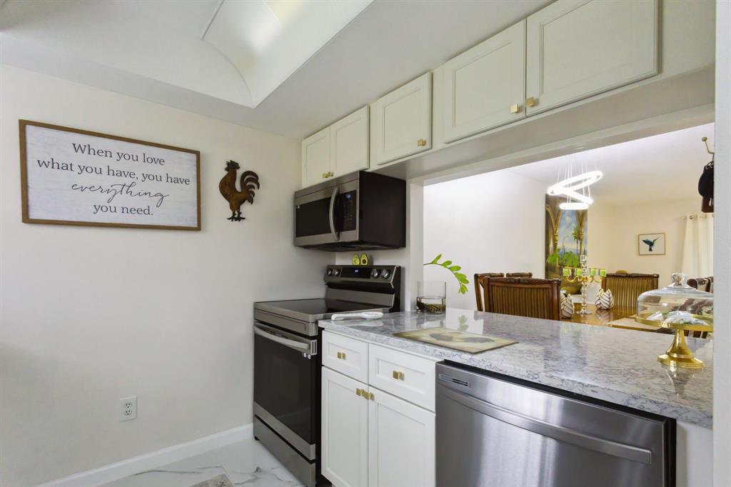 368 Waterside Drive Hypoluxo, FL 33462 - Photo 16 of 24 a kitchen with stainless steel appliances granite countertop a sink a stove a microwave and wooden cabinets