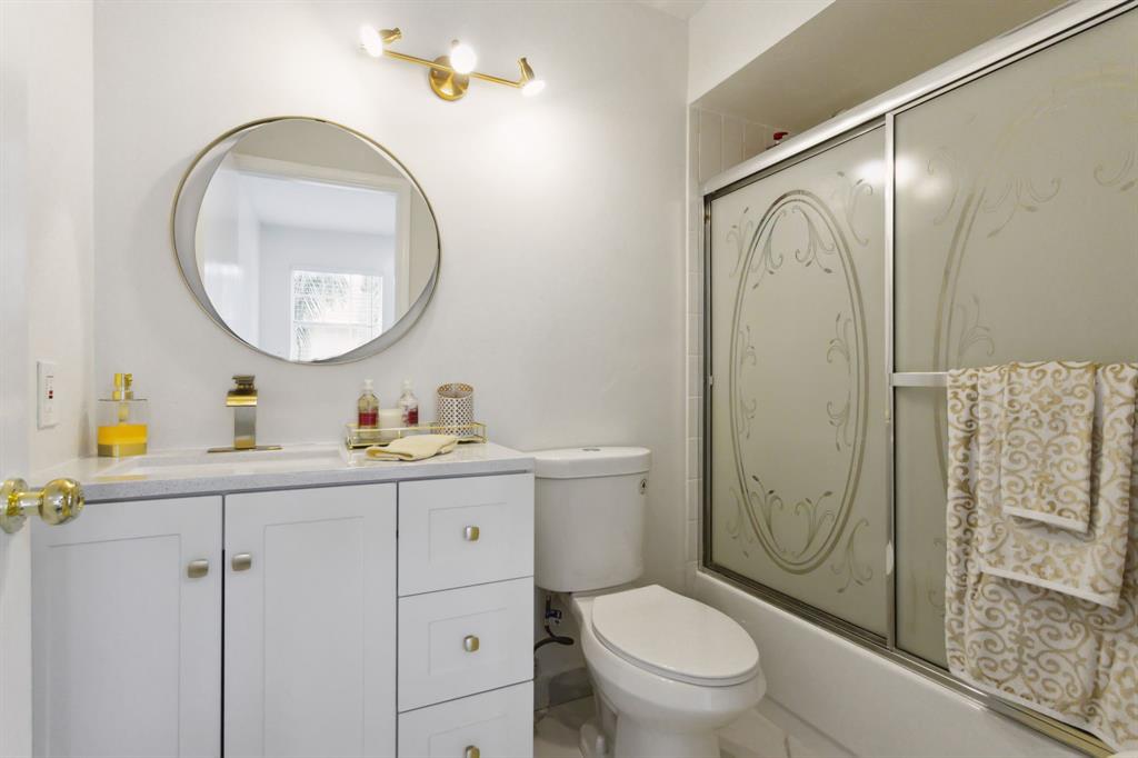 368 Waterside Drive Hypoluxo, FL 33462 - Photo 2 of 24 a bathroom with a toilet a sink a mirror a vanity and shower
