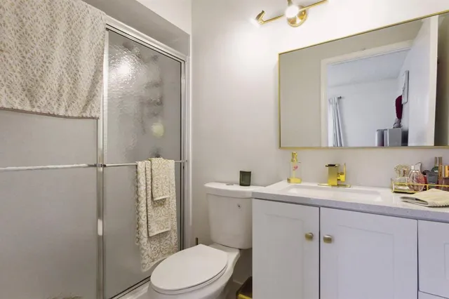 a bathroom with a toilet a sink a mirror a vanity and shower