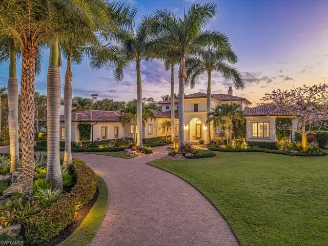 a front view of a house with a garden and palm trees