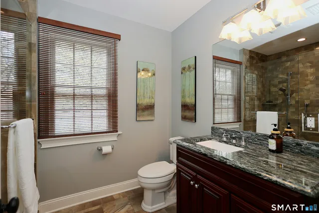 a bathroom with a granite countertop sink toilet and mirror