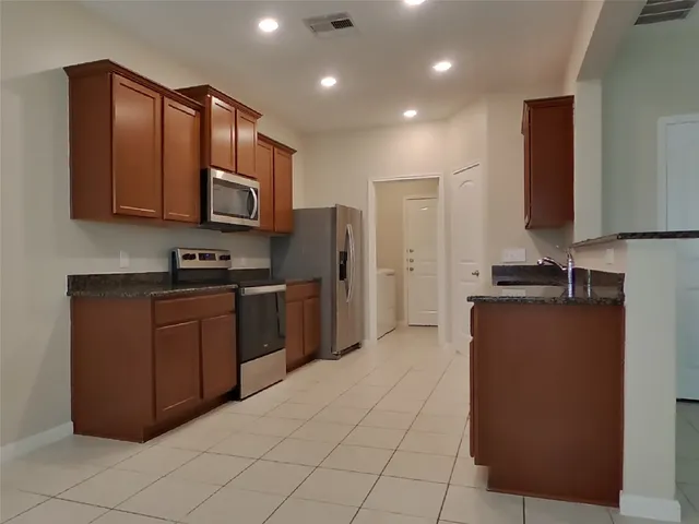 a kitchen with stainless steel appliances granite countertop a refrigerator and a stove top oven