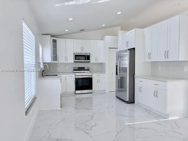 a kitchen with white cabinets and white appliances