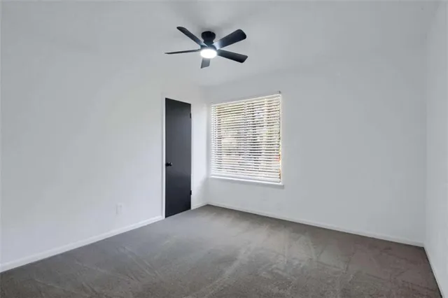 an empty room with ceiling fan and window