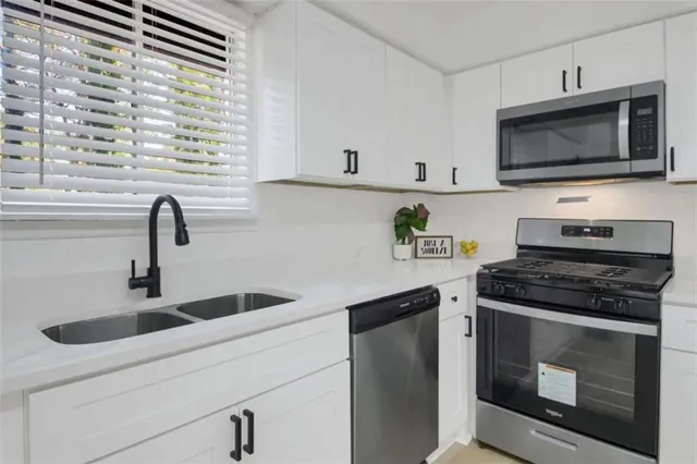 a kitchen with stainless steel appliances granite countertop a sink a stove a microwave and wooden cabinets