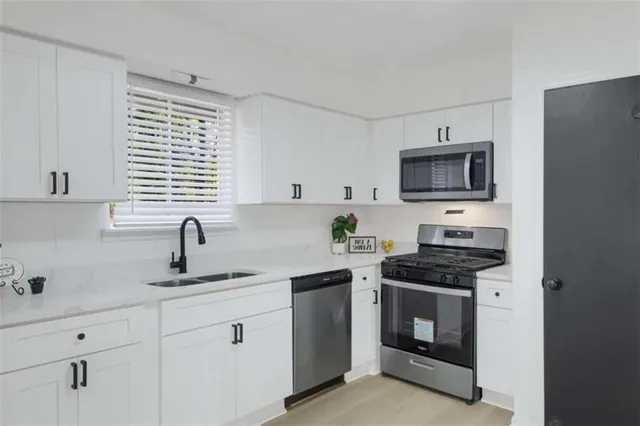 a kitchen with stainless steel appliances a stove sink microwave and cabinets