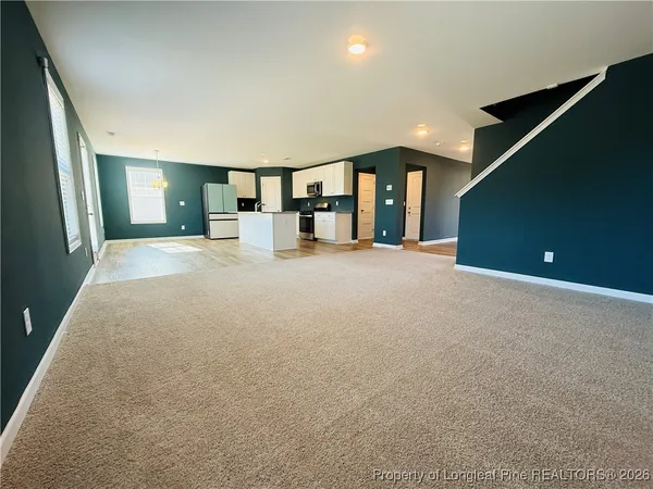 a view of an empty room with window and stairs