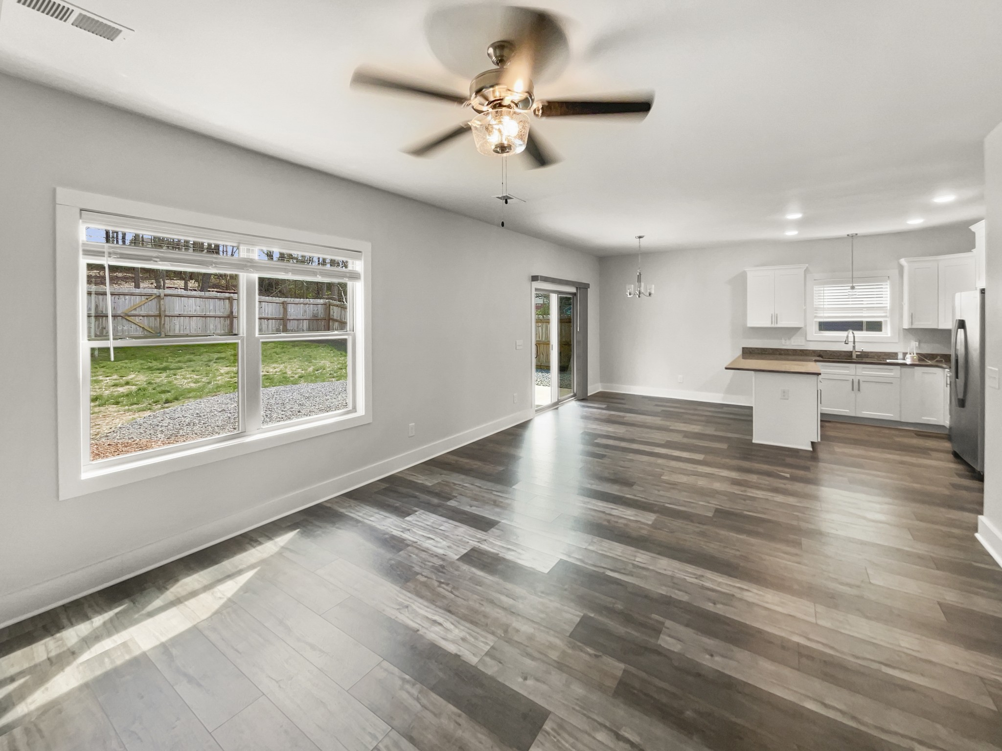 1672 Rains Road Clarksville, TN 37042 - Photo 8 of 23 a view of an empty room and kitchen with wooden floor and a ceiling fan