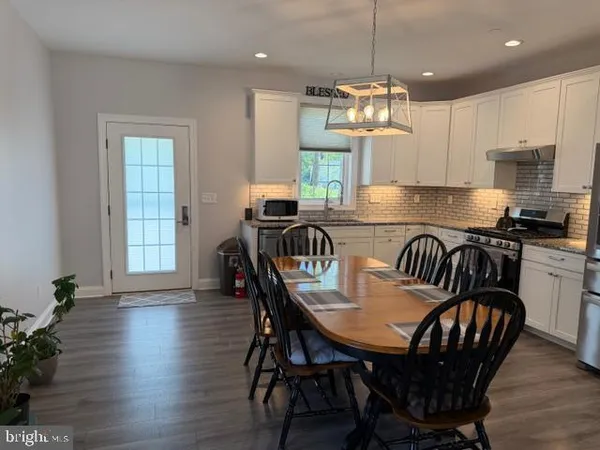 a kitchen with stainless steel appliances granite countertop a stove a sink and a refrigerator with wooden floor