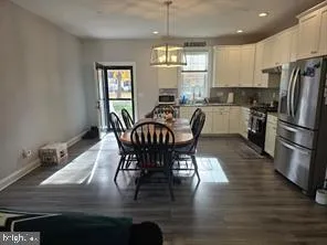 a kitchen with stainless steel appliances granite countertop a stove a sink a microwave oven a dining table and chairs with wooden floor