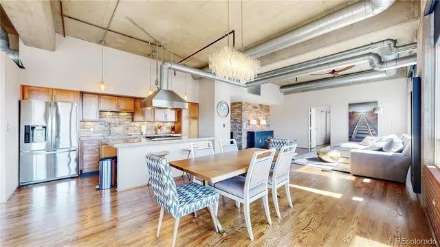 a kitchen with stainless steel appliances granite countertop a dining table chairs refrigerator and stove