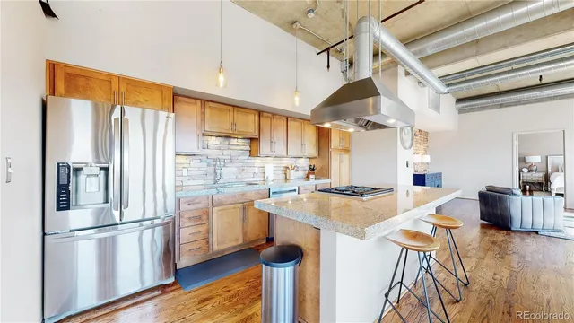 a kitchen with stainless steel appliances granite countertop a refrigerator a stove and white cabinets with wooden floors