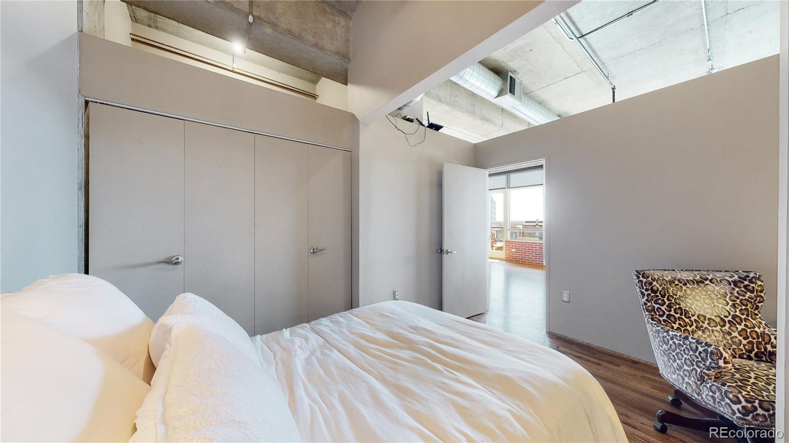 2000 Little Raven Street, Unit 702 Denver, CO 80202 - Photo 21 of 48 a bedroom with a bed and a chandelier