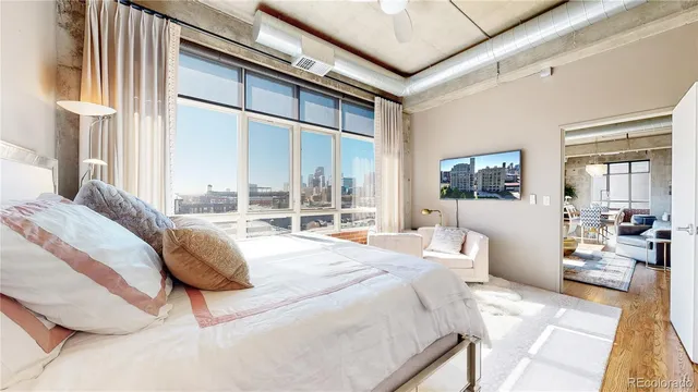 a bedroom with a bed couch and large window with outer view