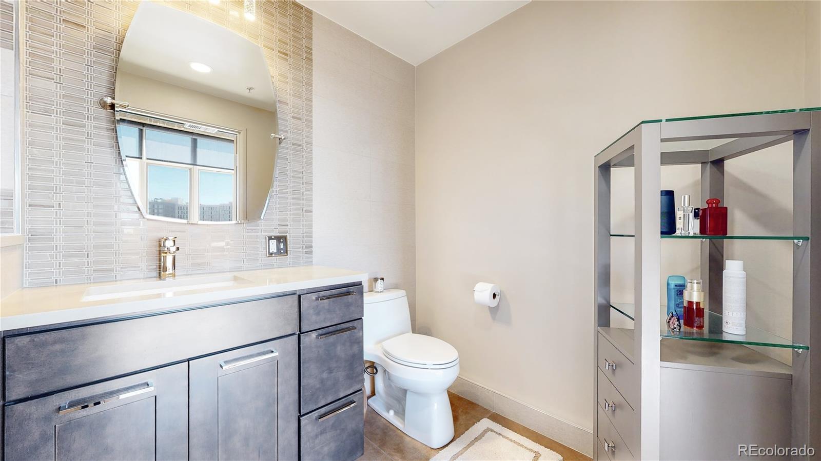 2000 Little Raven Street, Unit 702 Denver, CO 80202 - Photo 28 of 48 a bathroom with a toilet sink a mirror and vanity