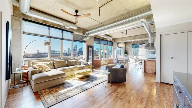 a living room with furniture large window and wooden floor