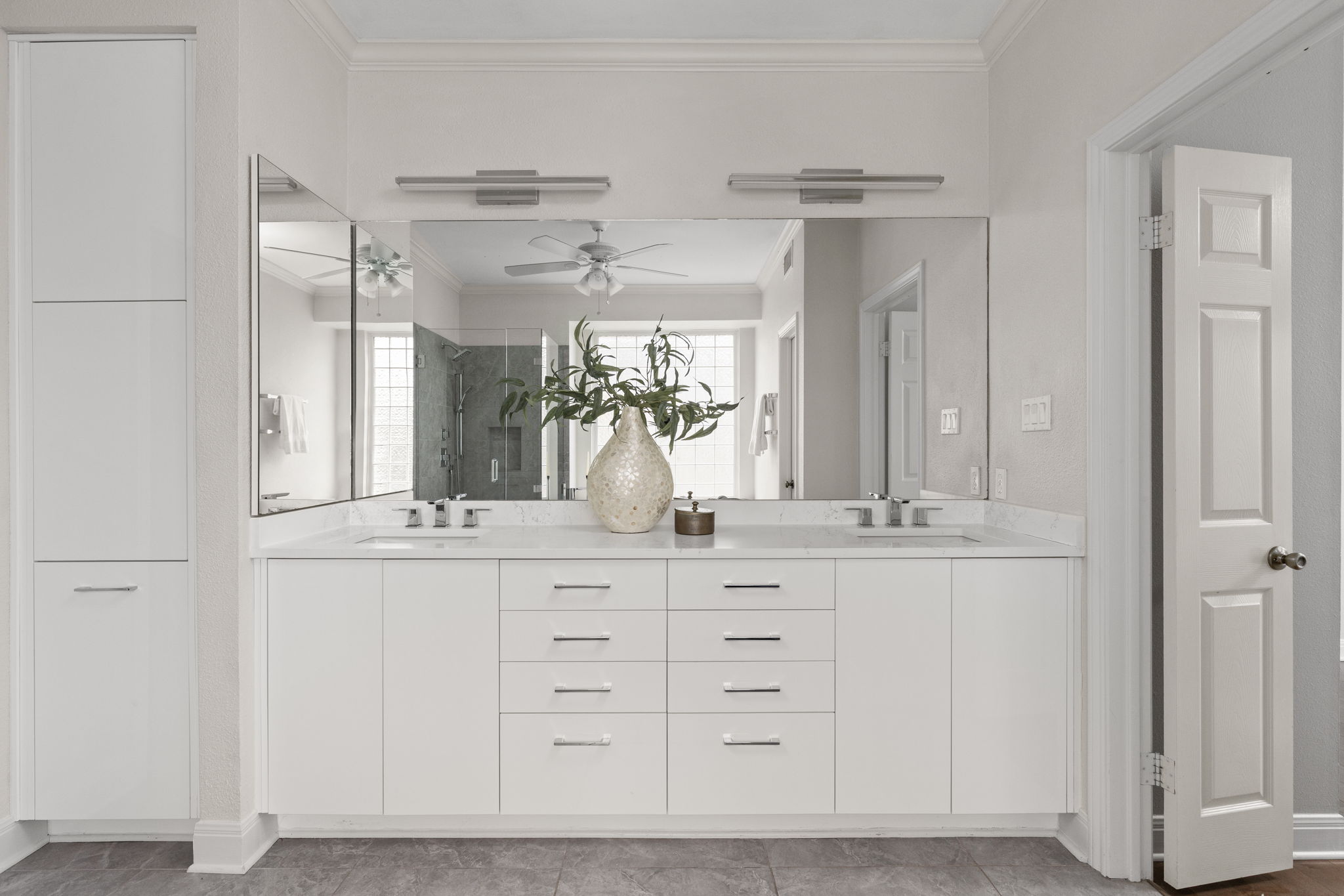 2807 Round Table Road Austin, TX 78746 - Photo 17 of 40 White double vanity with integrated sinks, white countertops, extensive under-sink cabinetry, and three large mirrors