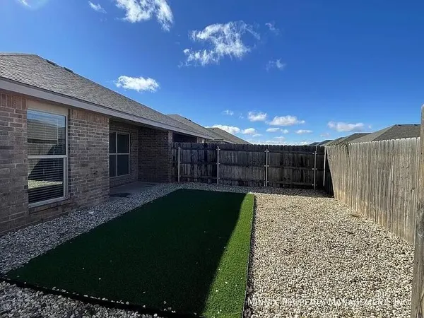 a view of a backyard with brick wall plants and a bench