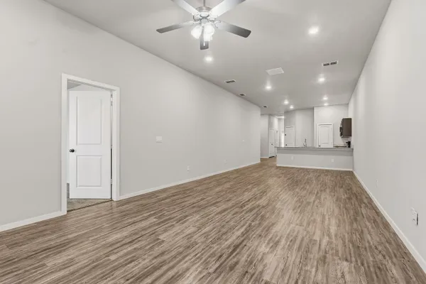 an empty room with a chandelier fan and windows