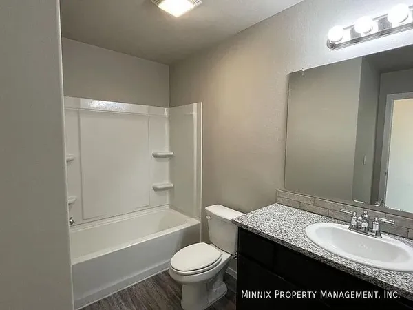 a bathroom with a granite countertop sink toilet mirror and shower