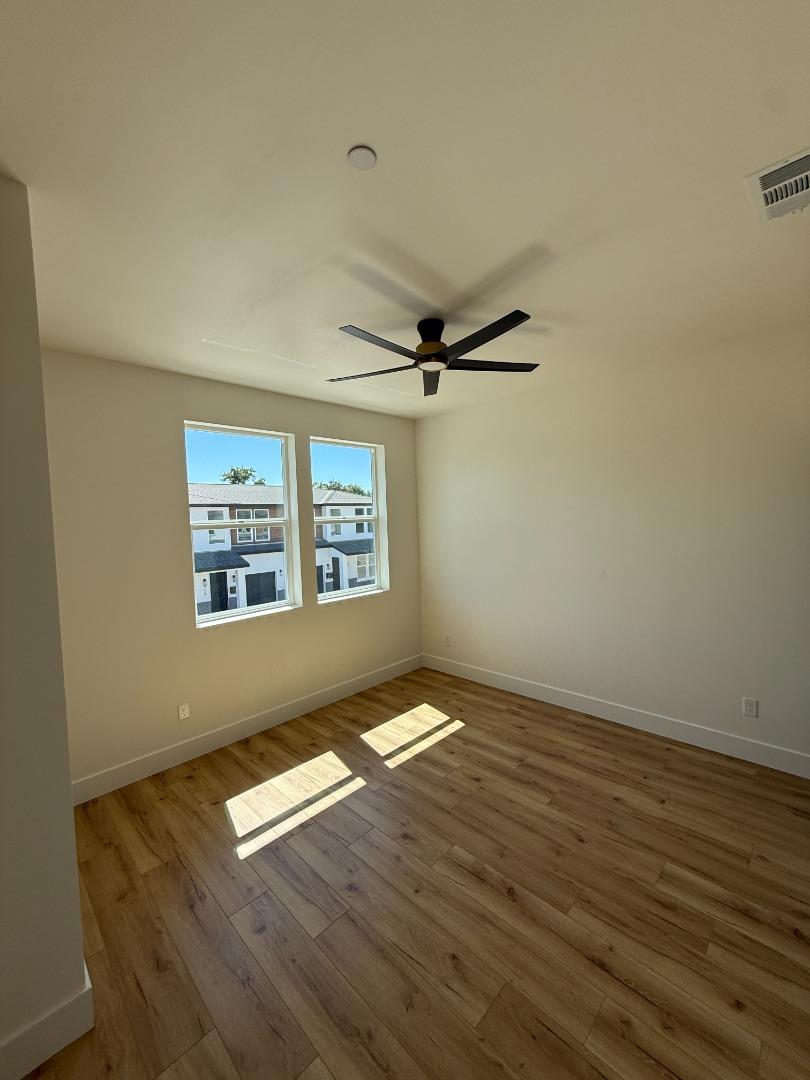 963 Olive Br Place, Unit 959 Sacramento, CA 95815 - Photo 5 of 12 an empty room with wooden floor fan and windows