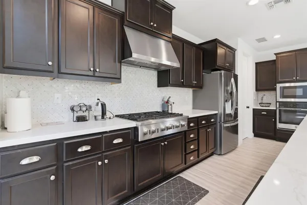 a kitchen with stainless steel appliances granite countertop a sink a stove a refrigerator and a microwave with wooden floor