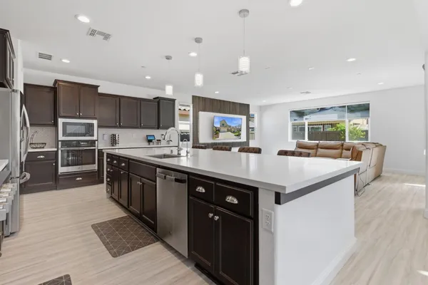 a kitchen with stainless steel appliances a sink dishwasher a refrigerator and a stove with wooden floor