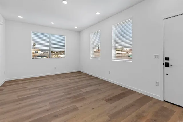 an empty room with wooden floor and windows