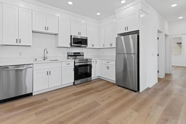 a kitchen with stainless steel appliances granite countertop a refrigerator sink and white cabinets