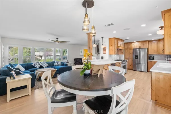 a kitchen with stainless steel appliances granite countertop a sink a stove a refrigerator and island with wooden floor