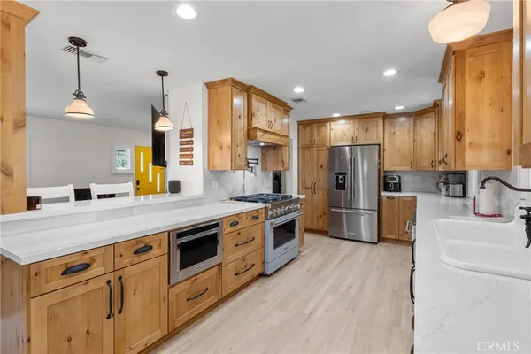 a kitchen with stainless steel appliances a stove a sink dishwasher and cabinets with wooden floor